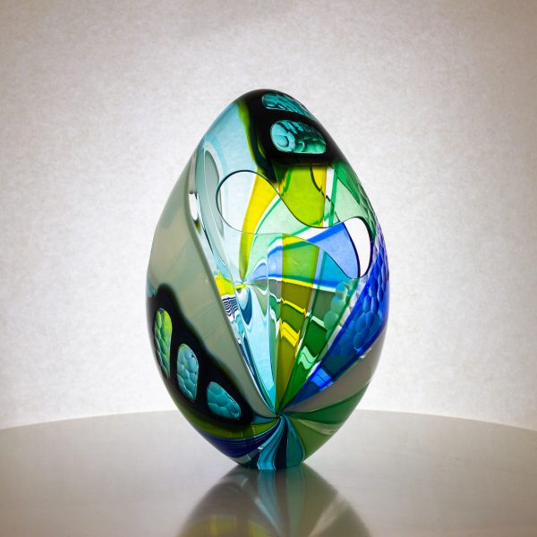 Green and blue striped hand blown glass egg. This egg has cut outs and carved texture on the surface.